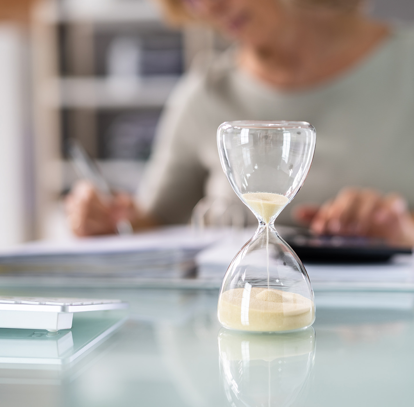 Image of hourglass and woman working 